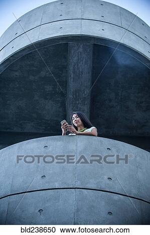 Low angle view of businesswoman on balcony texting on cell phone View Large Photo Image Stock Image - Low angle view of businesswoman on balcony texting on cell phone. Fotosearch