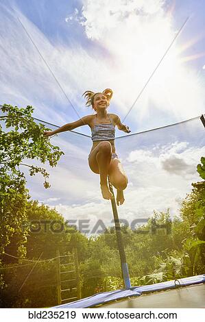 Low angle view of Caucasian girl jumping on trampoline View Large Photo Image Stock Photo - Low angle view of Caucasian girl jumping on trampoline. Fotosearch