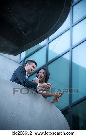 Low angle view of couple on balcony texting on cell phones View Large Photo Image Stock Image - Low angle view of couple on balcony texting on cell phones. Fotosearch