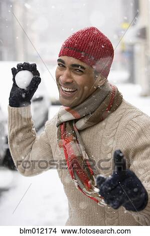Picture - Man aiming snowball in city. Fotosearch