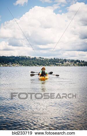 Stock Photo - Man and woman in kayak holding paddles. Fotosearch