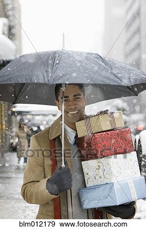 Stock Photo - Man carrying Christmas gifts in city. Fotosearch