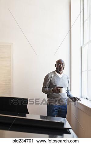 Man drinking coffee near window View Large Photo Image Stock Image - Man drinking coffee near window. Fotosearch