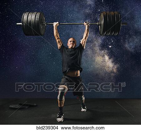 Man lifting heavy barbell against starry sky View Large Photo Image Picture - Man lifting heavy barbell against starry sky. Fotosearch