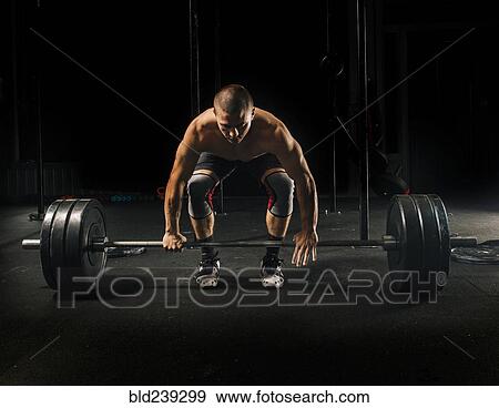 Man lifting heavy barbell in gymnasium View Large Photo Image Stock Photo - Man lifting heavy barbell in gymnasium. Fotosearch