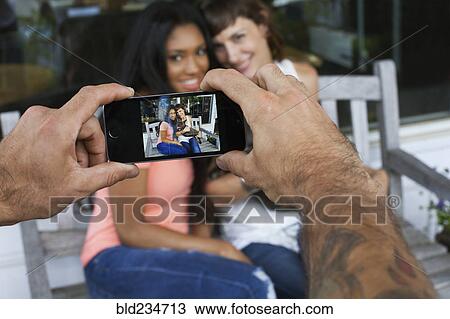 Man photographing women with cell phone View Large Photo Image Stock Image - Man photographing women with cell phone. Fotosearch
