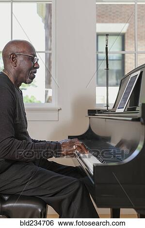 Stock Photograph - Man playing piano near window. Fotosearch