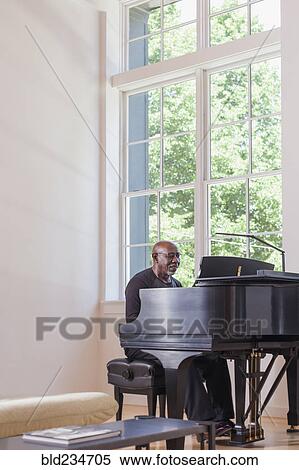 Stock Photography - Man playing piano near window. Fotosearch