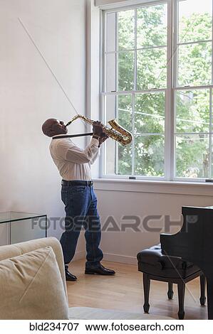 Man playing saxophone near window View Large Photo Image Stock Photo - Man playing saxophone near window. Fotosearch