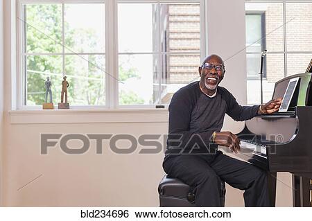 Man sitting at piano with digital tablet near window View Large Photo Image Stock Photograph - Man sitting at piano with digital tablet near window. Fotosearch