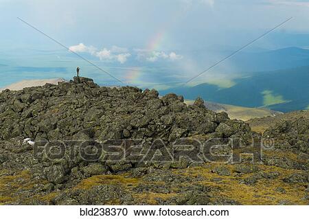 Man standing on rock formation looking at rainbow View Large Photo Image Stock Image - Man standing on rock formation looking at rainbow. Fotosearch