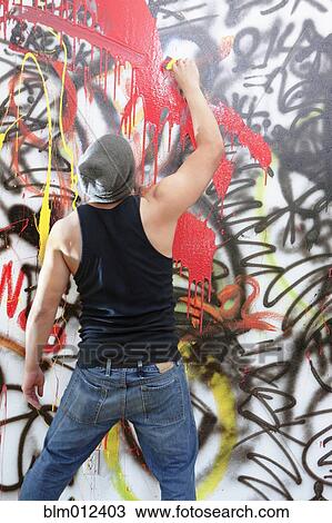 Stock Image - Man tagging wall with graffiti. Fotosearch