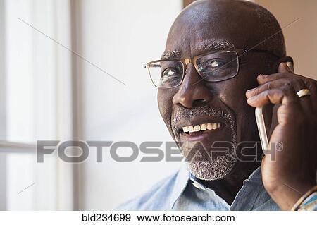 Man talking on cell phone near window View Large Photo Image Stock Photo - Man talking on cell phone near window. Fotosearch