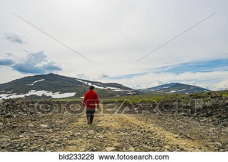 Stock Photo - Man walking on mountain path in winter. Fotosearch
