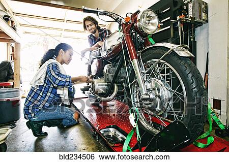 Man watching woman repairing motorcycle in garage View Large Photo Image Stock Photograph - Man watching woman repairing motorcycle in garage. Fotosearch