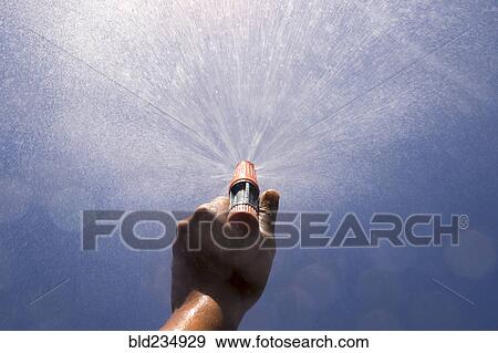 Stock Photo - Mari boy spraying nozzle to blue sky. Fotosearch