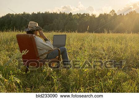 Mari man sitting on chair in field using laptop View Large Photo Image Stock Image - Mari man sitting on chair in field using laptop. Fotosearch