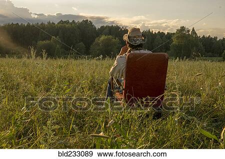 Stock Photo - Mari man sitting on chair in field. Fotosearch