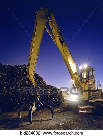 Stock Image - Mechanical grabber in junkyard at night. Fotosearch
