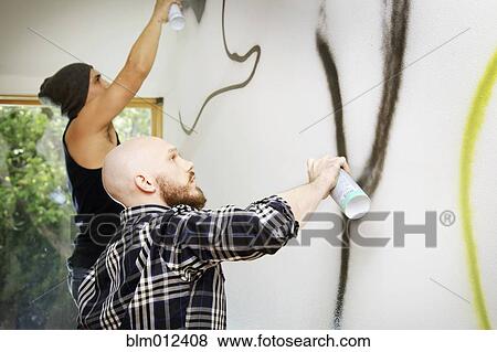 Stock Photo - Men tagging wall with graffiti. Fotosearch