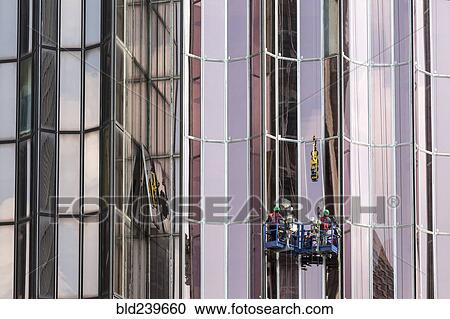 Stock Image - Men washing windows on skyscraper. Fotosearch