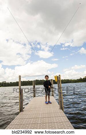 Stock Image - Mixed race boy fishing on dock. Fotosearch