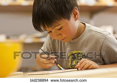 Picture - Mixed Race boy painting in art class. Fotosearch