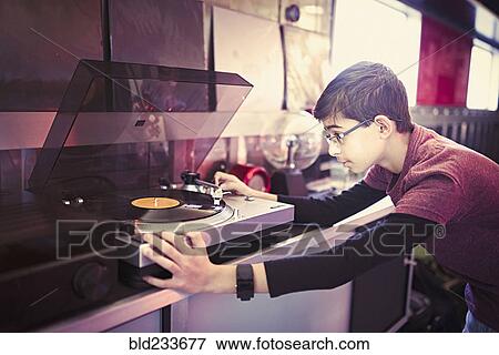 Stock Photo - Mixed Race boy playing vinyl record on turntable. Fotosearch