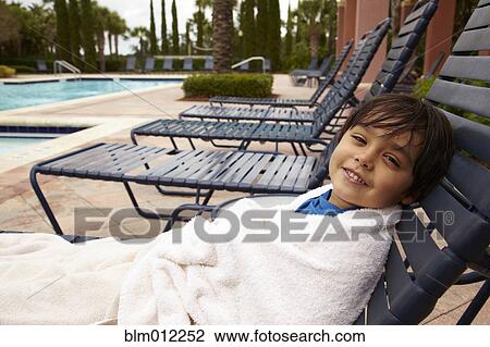 Mixed race boy reclining on lounge chair at poolside View Large Photo Image Stock Image - Mixed race boy reclining on lounge chair at poolside. Fotosearch