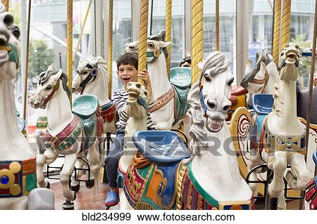 Stock Photo - Mixed race boy riding carousel. Fotosearch