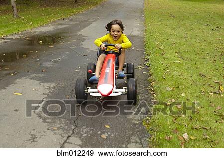 Stock Photo - Mixed race boy riding toy car. Fotosearch