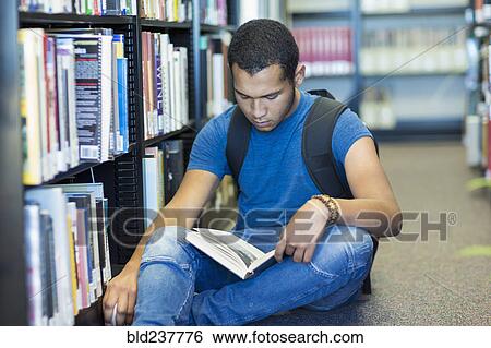 Mixed Race boy sitting on floor reading book in library View Large Photo Image Stock Photograph - Mixed Race boy sitting on floor reading book in library. Fotosearch