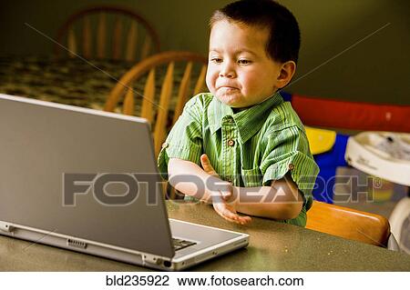 Stock Image - Mixed Race boy using laptop. Fotosearch
