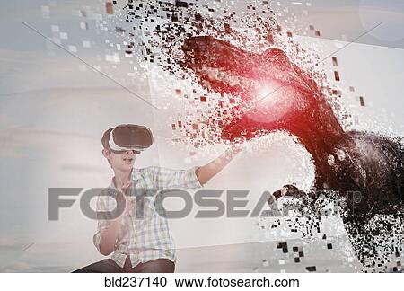 Stock Image - Mixed Race boy using virtual reality goggles watching dinosaur. Fotosearch