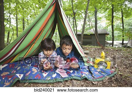 Stock Image - Mixed Race boys playing card game in blanket fort. Fotosearch