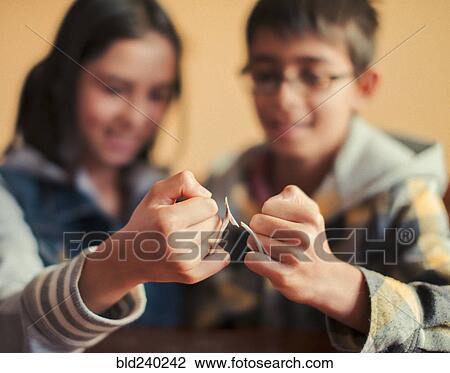 Stock Image - Mixed Race brother and sister snapping wishbone. Fotosearch
