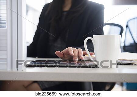 Stock Photo - Mixed Race businesswoman using digital tablet in office. Fotosearch
