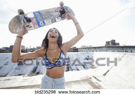 Mixed Race celebrating on rooftop with skateboard View Large Photo Image Stock Photo - Mixed Race celebrating on rooftop with skateboard. Fotosearch
