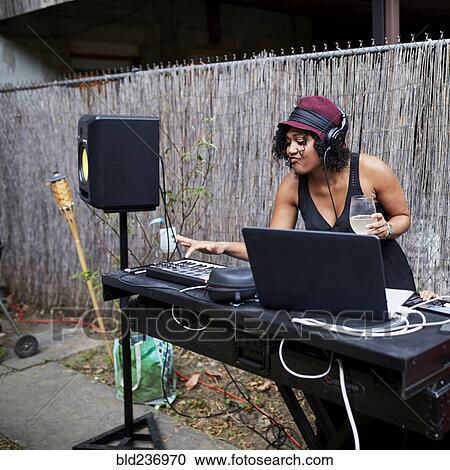 Stock Image - Mixed Race dj playing music in backyard. Fotosearch
