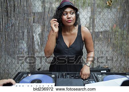 Stock Image - Mixed Race dj playing music in backyard. Fotosearch