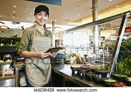 Stock Photo - Mixed Race food court worker using digital tablet. Fotosearch