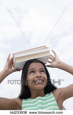 Stock Photo - Mixed Race girl balancing books on head. Fotosearch