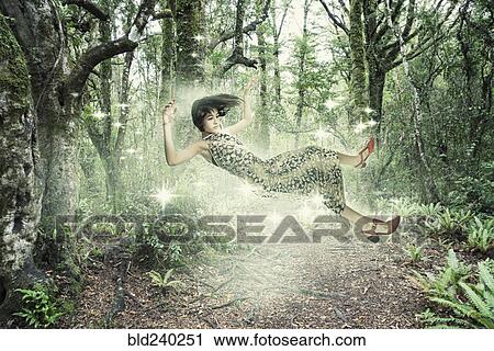 Stock Image - Mixed Race girl floating in forest. Fotosearch