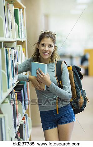 Stock Photography - Mixed Race girl holding book in library. Fotosearch