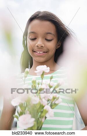 Stock Image - Mixed Race girl holding bouquet of flowers. Fotosearch