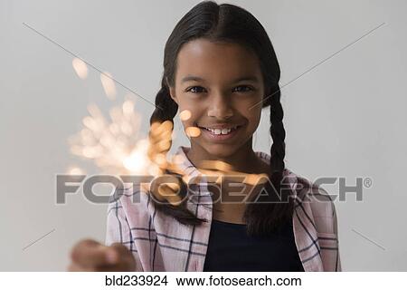 Picture - Mixed Race girl holding sparkler. Fotosearch