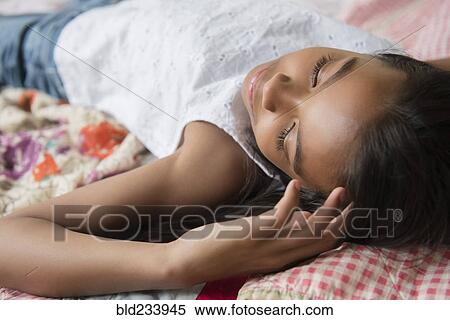 Stock Photography - Mixed Race girl laying on bed napping. Fotosearch