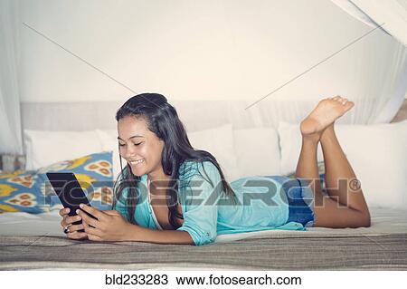 Mixed Race girl laying on bed reading digital tablet View Large Photo Image Stock Image - Mixed Race girl laying on bed reading digital tablet. Fotosearch