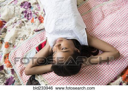 Mixed Race girl laying on bed with hands behind head View Large Photo Image Stock Photograph - Mixed Race girl laying on bed with hands behind head. Fotosearch
