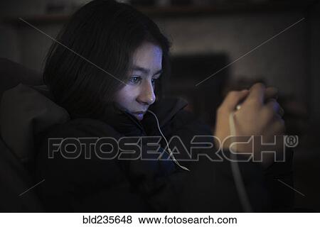 Mixed Race girl listening to cell phone with earbuds View Large Photo Image Stock Photo - Mixed Race girl listening to cell phone with earbuds. Fotosearch